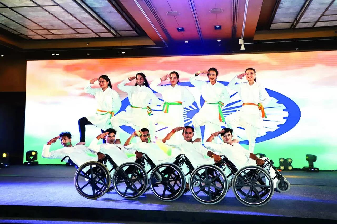 Wheelchair dancers performing in white in front of a tricolour backdrop
